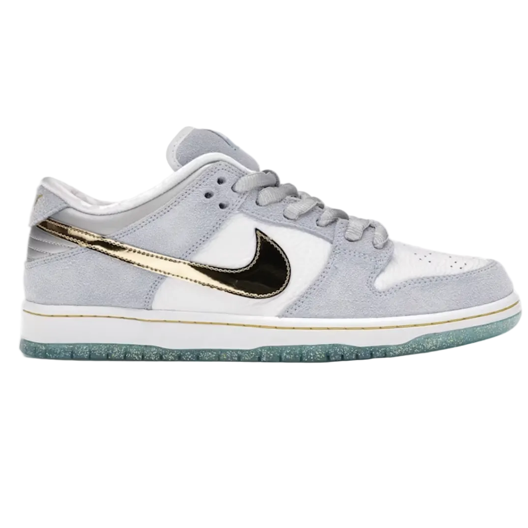 A Nike Dunk sneaker in light gray suede and leather with a metallic gold Swoosh, a black Swoosh overlay, and a white midsole, shown against a plain white background.