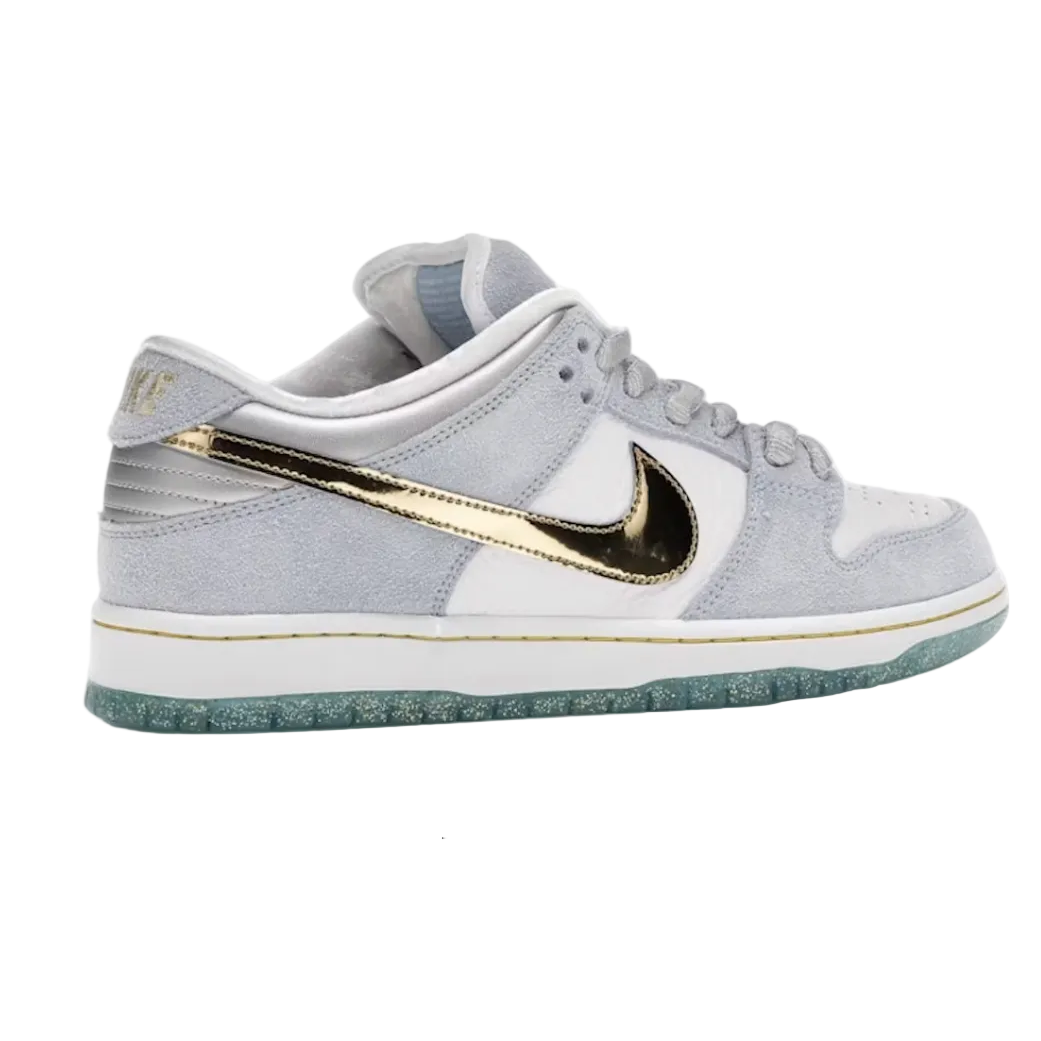 A Nike Dunk sneaker in light gray suede and leather with a metallic gold Swoosh, white midsole, and a translucent teal outsole, shown against a plain white background.
