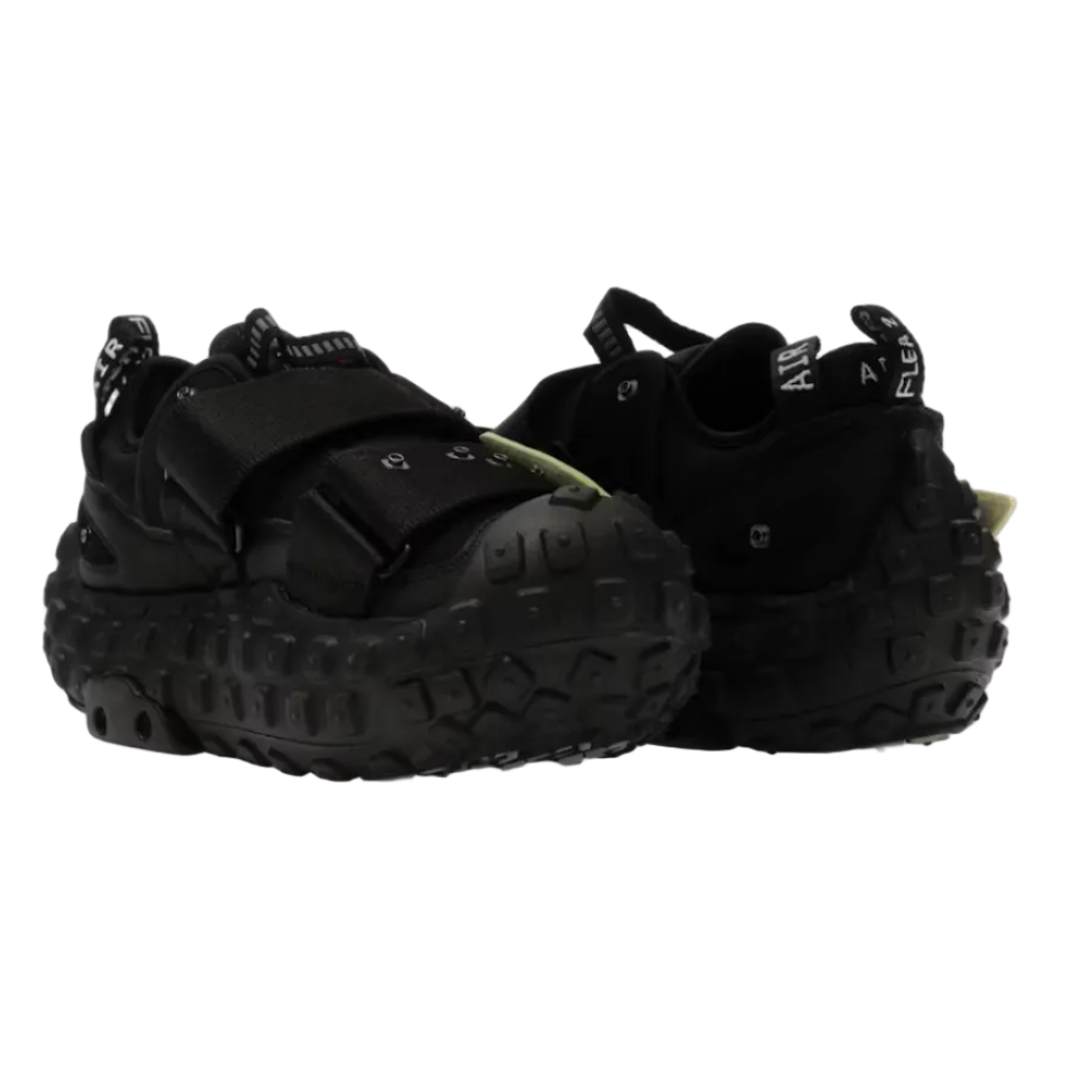 A pair of black chunky platform sneakers with thick textured soles and hook-and-loop strap closures, shown from the side on a white background.