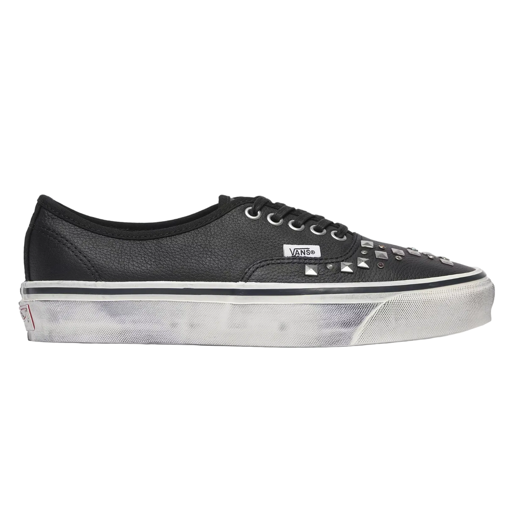A black leather Vans platform sneaker with silver studs on the toe box, shown in a side profile against a light gray background.