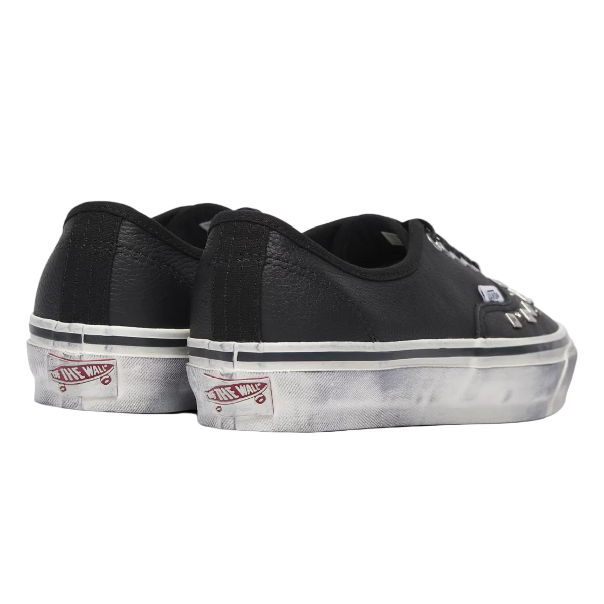 A pair of black leather Vans Authentic low-top sneakers with distressed white rubber soles, shown from a three-quarters rear angle on a light gray background.